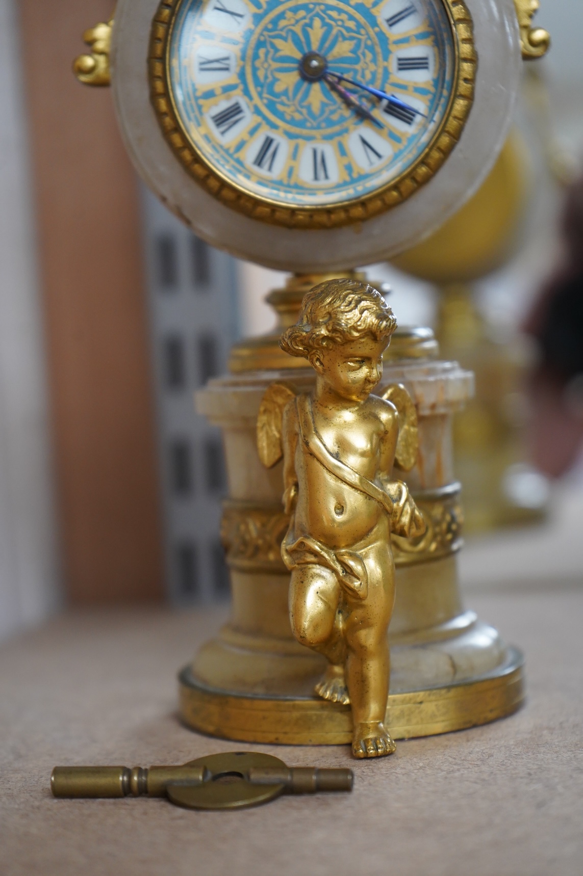 A late 19th century French ormolu and alabaster timepiece with painted dial and key, 24cm high